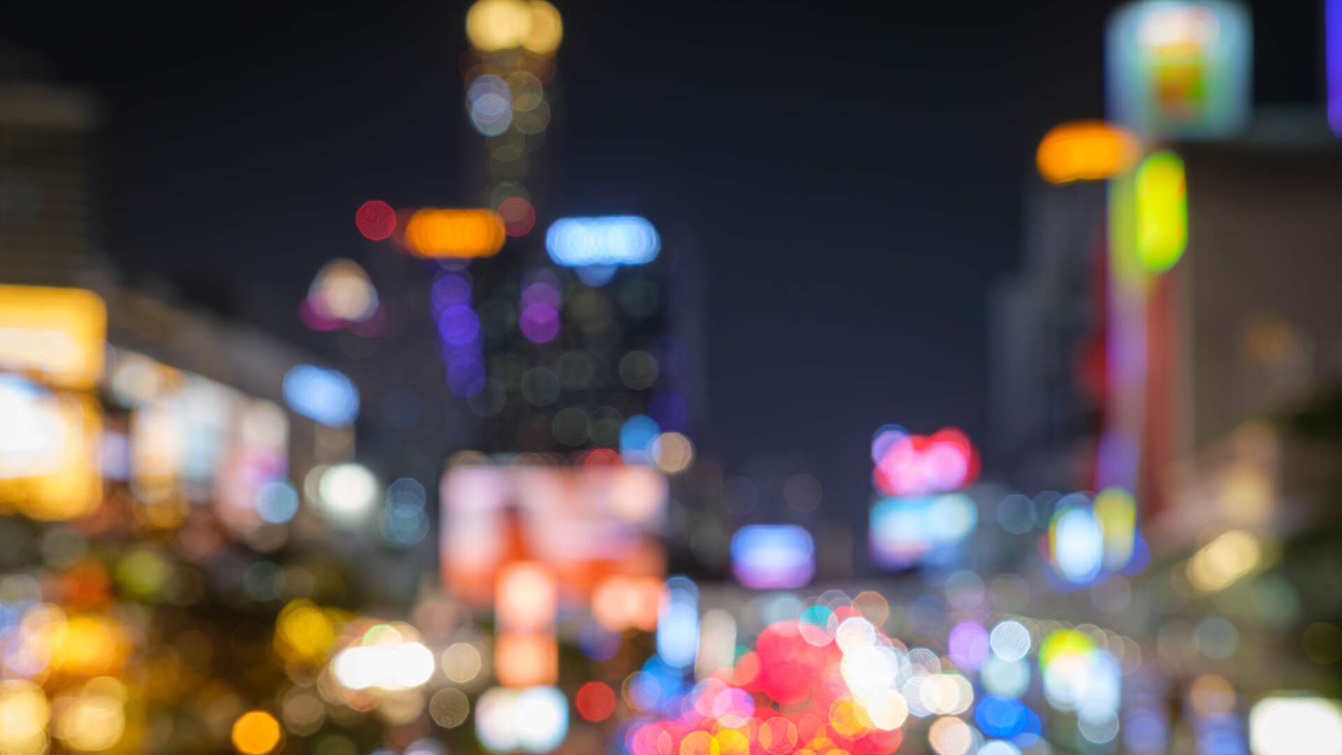 Abstract blurred background cityscape of Krung Thep Maha Nakhon (Bangkok) on night scene with multicolour bokeh from neon light on building