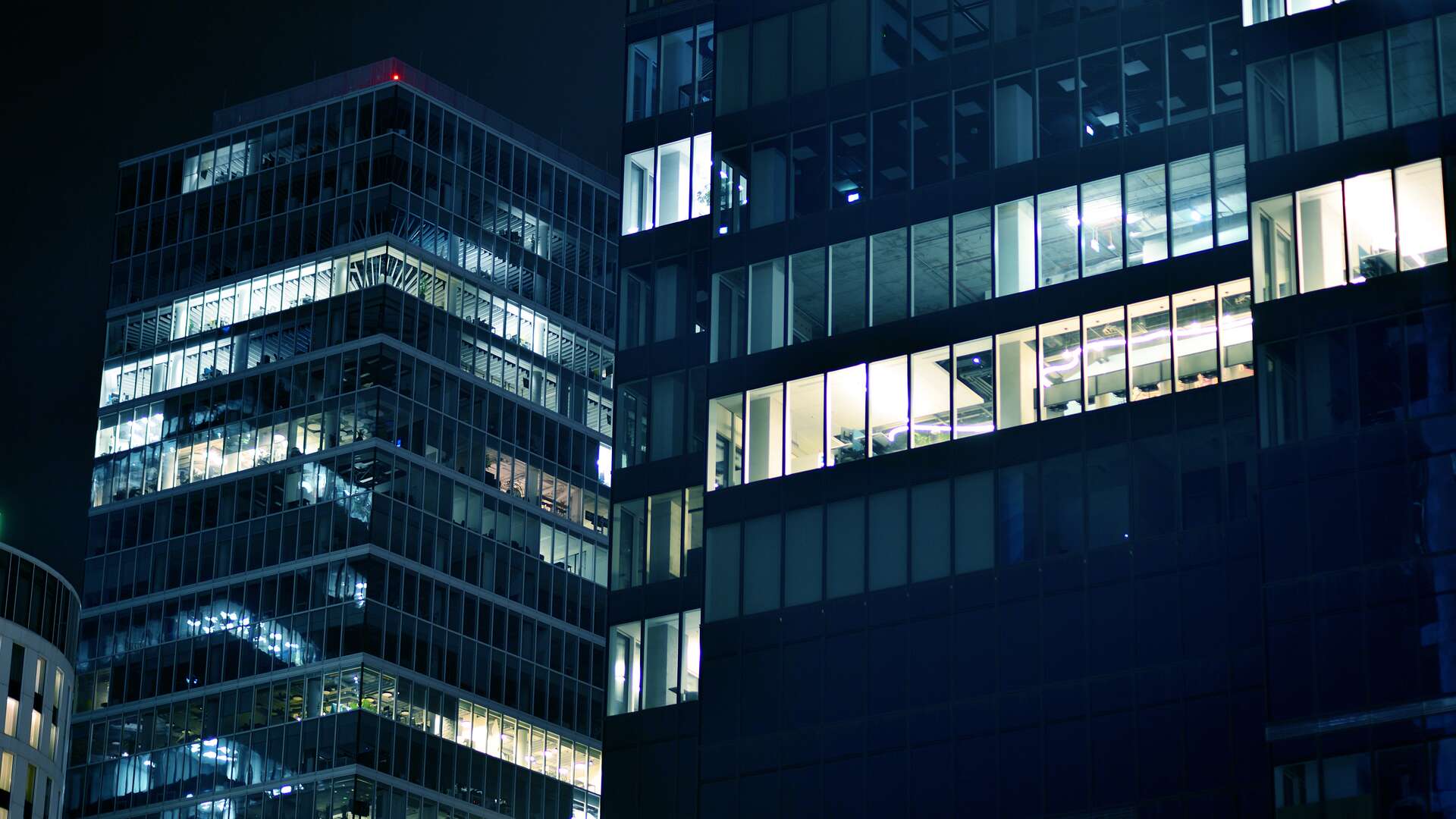 Pattern of office buildings windows illuminated at night. Glass architecture ,corporate building at night - business concept. Blue graphic filter